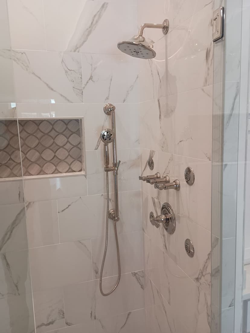 Modern shower with marble tiles, rainfall showerhead, and polished chrome fixtures.