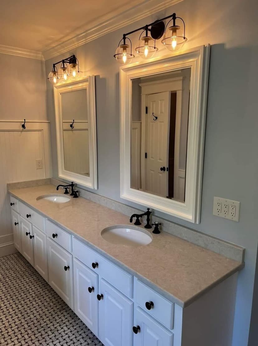 Modern bathroom with double sinks, elegant mirrors, and stylish lighting fixtures.